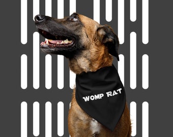 May include: A brown and black dog wearing a black bandana with the text "WOMP RAT" in white letters. The dog is looking up and has its mouth open.