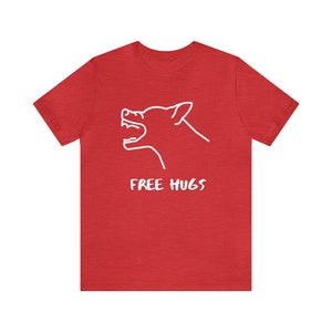 Könnte beinhalten: Rotes T-Shirt mit einer weißen Strichzeichnung eines heulenden Wolfs und dem weißen Schriftzug "FREE HUGS". Das Shirt ist einfarbig rot und hat kurze Ärmel.