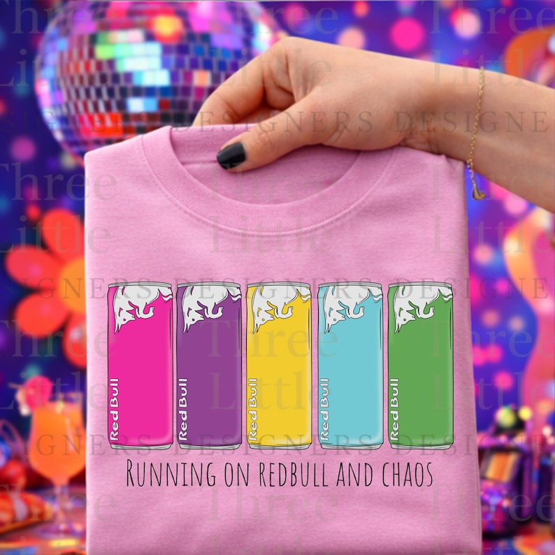 May include: Pink crew neck sweatshirt with a graphic of five colorful Red Bull cans. The cans are in shades of pink, purple, yellow, blue, and green. The text "RUNNING ON REDBULL AND CHAOS" is printed below the cans.