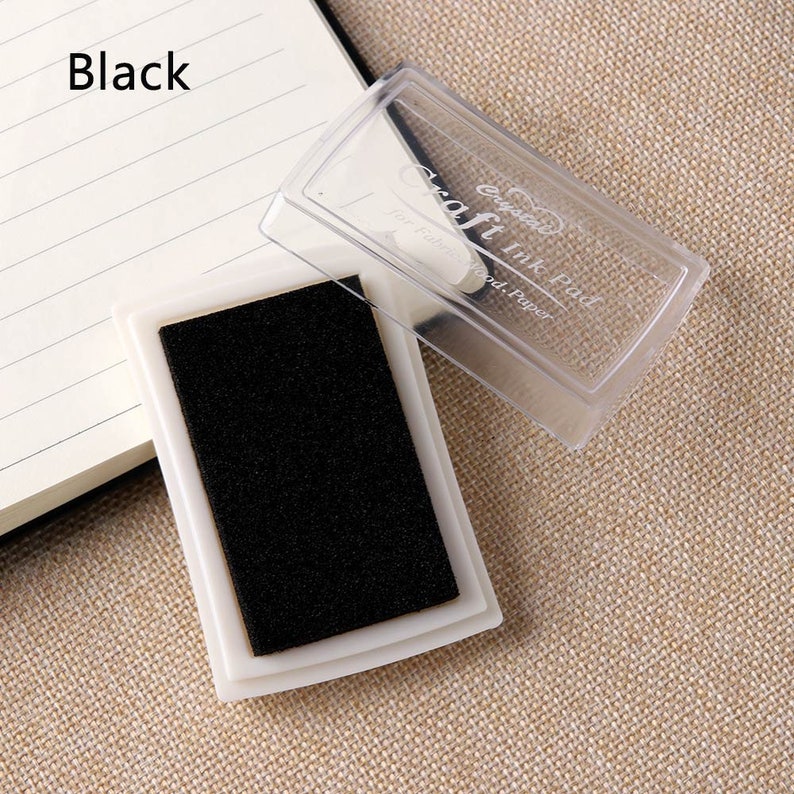 May include: Black ink pad in a clear plastic case. The case has the text "Craft Ink Pad" on it.