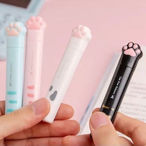 以下が含まれることがあります： ピンク、ブルー、白、黒のハンドルが付いた猫の足の形をしたハサミ4本。ハサミには、黒いハンドルに「Cat Paw Scissors」という文字が印刷されています。