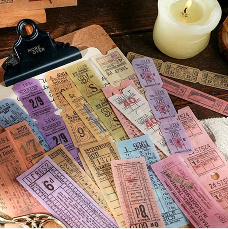 Pu&ograve; includere: Una collezione di adesivi per biglietti in stile vintage in vari colori, tra cui rosa, viola, blu e giallo. Gli adesivi presentano numeri, lettere e parole come "Ryedale Motors" e "Trasporti Pubblici".
