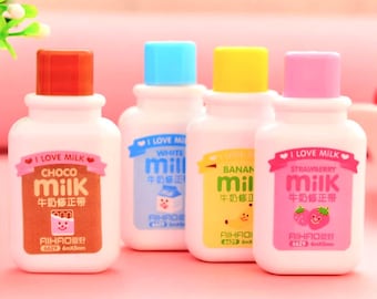 Puede incluir: Cuatro pequeños frascos de plástico de líquido corrector con tapas de diferentes colores y diseños de cajas de leche de dibujos animados. Los frascos están etiquetados con "I Love Milk" y tienen diferentes sabores: Choco, Blanco, Plátano y Fresa. Cada frasco tiene un lindo personaje de dibujos animados en la etiqueta.