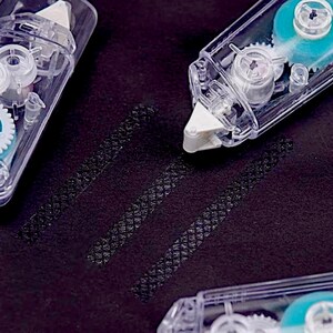 May include: Three clear plastic tape dispensers with blue and white gears. The dispensers are on a black surface with three lines of tape.