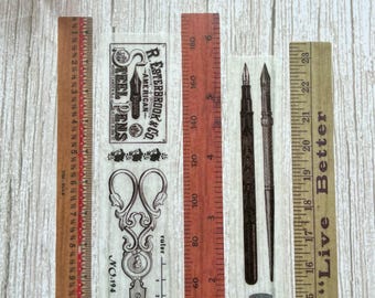 May include: Three vintage-style decorative paper tapes featuring a ruler, scissors, and an inkwell with a pen. The ruler is red and has markings in inches. The scissors are black and have an ornate design. The inkwell is black and has a label that reads "Thomas Black Ink". The pen is black with a gold nib. All three paper tapes are brown and have a vintage aesthetic.