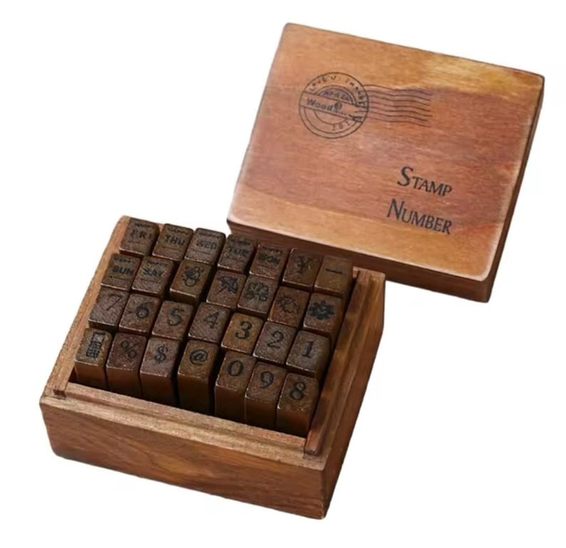 May include: A wooden box with a set of 30 alphabet and number stamps. The box is brown and has a label that says "Stamp Number". The stamps are arranged in rows and are made of wood.