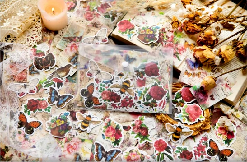 May include: A clear plastic bag filled with colorful vintage-style stickers featuring butterflies, bees, and floral designs. The stickers are on a background of old paper with faded text and images.