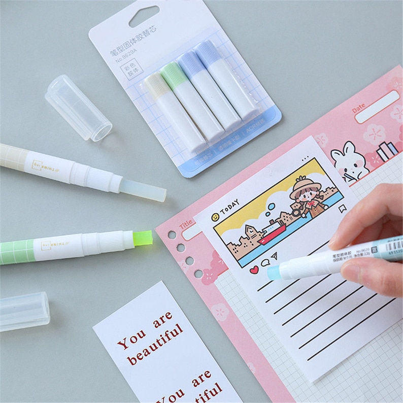 Puede incluir: Un juego de cuatro barras de pegamento blanco con tapas de colores azul, verde y verde claro. Las barras de pegamento est&aacute;n empaquetadas en una bolsa de pl&aacute;stico transparente con una etiqueta en caracteres chinos. Las barras de pegamento est&aacute;n sobre una superficie blanca. Tambi&eacute;n hay dos barras de pegamento retr&aacute;ctiles blancas y verdes con una tapa de pl&aacute;stico transparente sobre una superficie blanca. Las barras de pegamento se utilizan para borrar errores en un planificador rosa y blanco con un patr&oacute;n de cuadr&iacute;cula. El planificador tiene una ilustraci&oacute;n de dibujos animados de una ni&ntilde;a con un sombrero y un barco en una masa de agua. El planificador tambi&eacute;n tiene las palabras "T&iacute;tulo" y "HOY" escritas en &eacute;l.