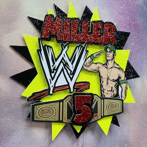 May include: A red glitter cake topper with the name "MILLER" and the number "5" in red glitter. The topper also features a black and white WWE logo, a gold WWE championship belt, and a cartoon image of John Cena in a green hat and black wristband.