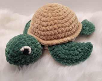 May include: A crocheted stuffed turtle toy with a brown shell and green body. The turtle has a black eye and a white eye.