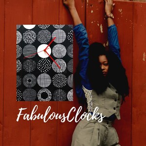 May include: A black and white clock with a red hour hand and a white face. The clock has a pattern of circles and lines. The text "Fabulous Clocks" is below the clock.