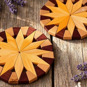 May include: Two circular wooden coasters featuring a central star pattern made of light tan wood, surrounded by a border of alternating dark brown and light tan wooden segments, creating a geometric design with a smooth, polished finish.