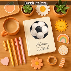 May include: A cream-coloured notebook featuring a soccer ball illustration and the text "Adrian's Notebook". The image also shows stationery items, including pens, stickers, and decorative tape in shades of orange, yellow, and pink, and small potted plants.