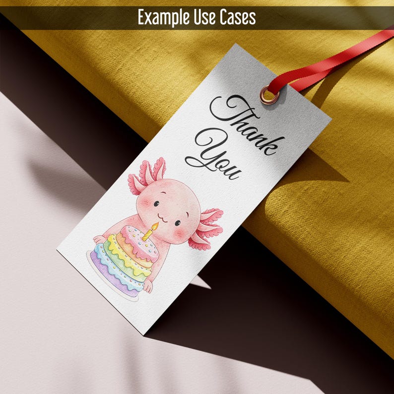 May include: A white tag with a red ribbon and the words "Thank You" in elegant script. The tag features a watercolor illustration of a pink axolotl holding a rainbow cake with a lit candle. The tag is designed for gift giving.