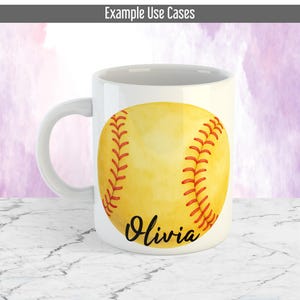 May include: White ceramic mug with a yellow softball design, red stitching, and the name "Olivia" in black script. The mug has a curved handle. The background is a marble surface.