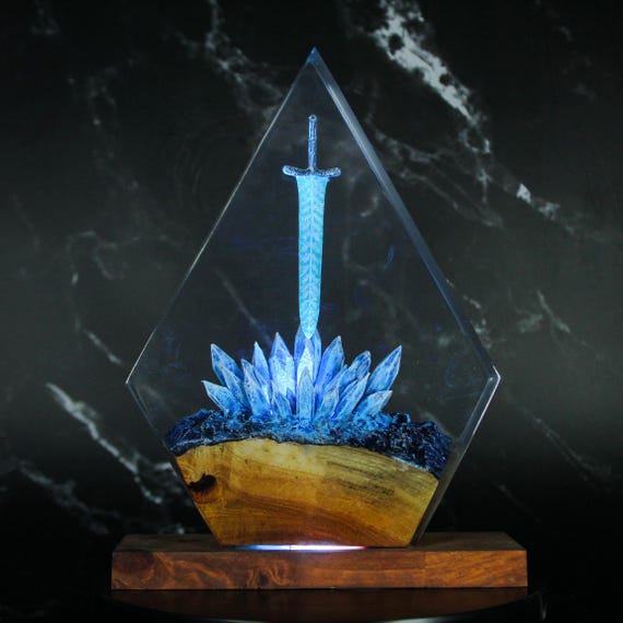 A glowing sword embedded in a dark moon resin block — genuinely striking fantasy desk art that doubles as a night light, with solid demand at 7 favorites.