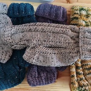 May include: Five knitted dog sweaters in different colors and patterns. The sweaters are made of a soft, textured yarn and have a variety of different stitch patterns. The sweaters are all in different sizes, but they are all designed to fit a small dog.