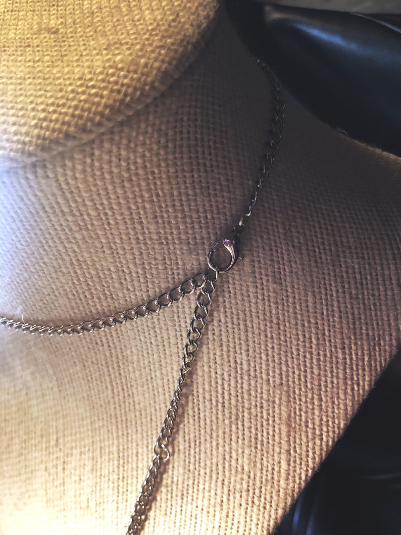 Pu&ograve; includere: Una collana a catena d'argento con chiusura a moschettone. La catena &egrave; su un manichino rivestito in tessuto.