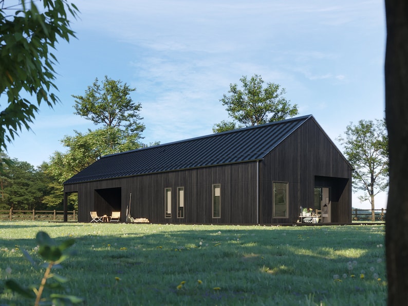 May include: A modern, black-clad house with a dark metal roof sits on a grassy lawn. The house has a simple, rectangular design with large windows and a covered porch area. Trees and a blue sky provide a natural backdrop.