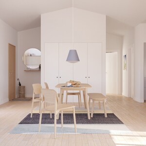 May include: A light-filled dining room featuring a wooden table, chairs, and a bench. A gray and blue rug sits beneath the table. A pendant light hangs above the table. The room has a minimalist design with white walls and wooden floors.