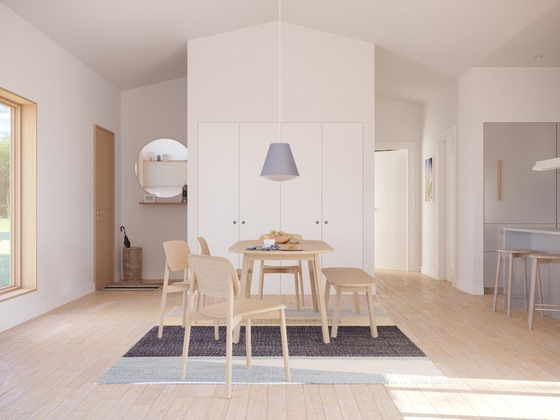 May include: A light-filled dining room featuring a wooden table, chairs, and a bench. A gray and blue rug sits beneath the table. A pendant light hangs above the table. The room has a minimalist design with white walls and wooden floors.