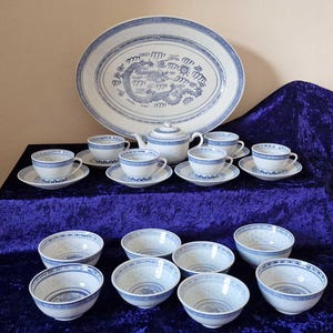 May include: A blue and white porcelain tea set featuring a dragon design. The set includes a teapot, cups, saucers, and bowls.