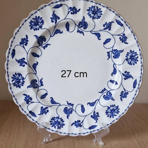 May include: A white ceramic plate with a blue floral design. The plate is 27 inches in diameter and has a scalloped edge.