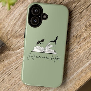 Könnte beinhalten: Eine salbeigrüne Handyhülle mit einer Schwarzweißillustration eines Buches, über dem zwei Drachen fliegen. Der Text "Just one more chapter" ist unter dem Buch gedruckt.