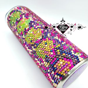 Puede incluir: Un vaso adornado con pedrería cubierto de pedrería iridiscente. El vaso presenta una vibrante mezcla de cristales rosas, verdes, amarillos y azules. El texto "Bling the Chaos" es visible.