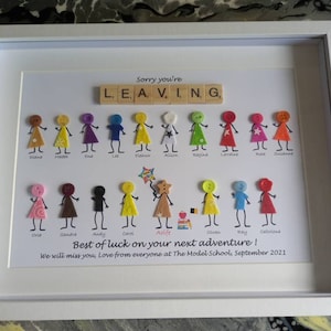 May include: A framed white board with a message that says "Sorry you're leaving" with the word "leaving" spelled out with letter tiles. There are 18 stick figures with different coloured buttons for heads and names written below each figure. The message "Best of luck on your next adventure! We will miss you. Love from everyone at The Model School, September 2021" is written at the bottom.