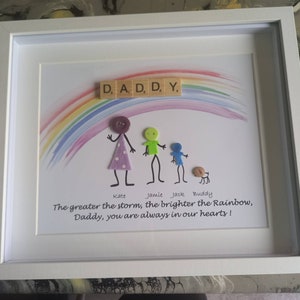 May include: A framed artwork with a rainbow painted on a white background. The words "D, A, D, D, Y." are spelled out with wooden letter tiles.  The words "The greater the storm, the brighter the Rainbow, Daddy, you are always in our hearts!" are written below the rainbow.  The artwork features a family of stick figures made with buttons and beads.