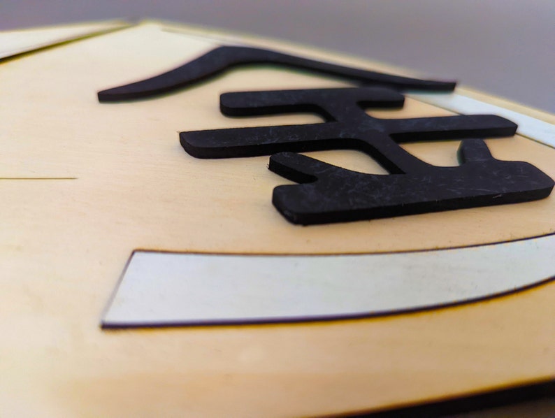May include: Close-up of a wooden sign with the Japanese character for "gold" written in black.