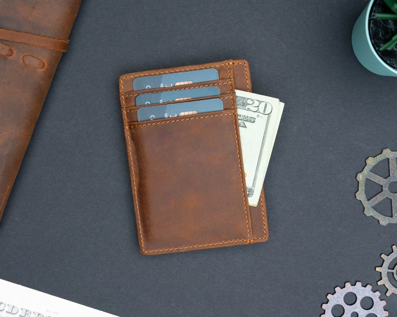 May include: A brown leather wallet with three credit cards and a twenty dollar bill inside.
