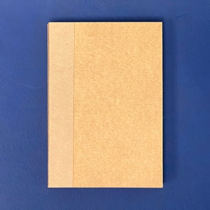May include: A brown notebook with a tan spine. The notebook is on a blue background.