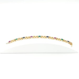 May include: A gold bracelet with alternating green, blue, and red gemstones.