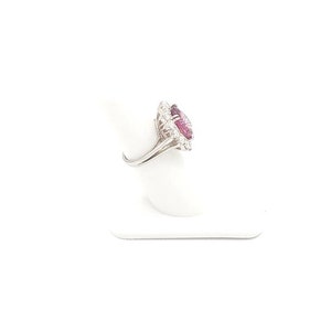 May include: A silver ring with a large pink gemstone surrounded by smaller white gemstones.