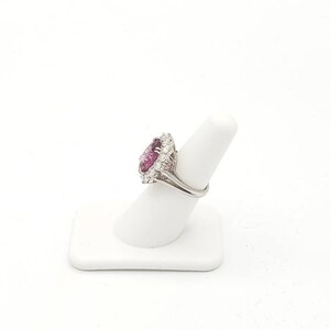 May include: A silver ring with a large, heart-shaped pink gemstone surrounded by smaller, clear gemstones.