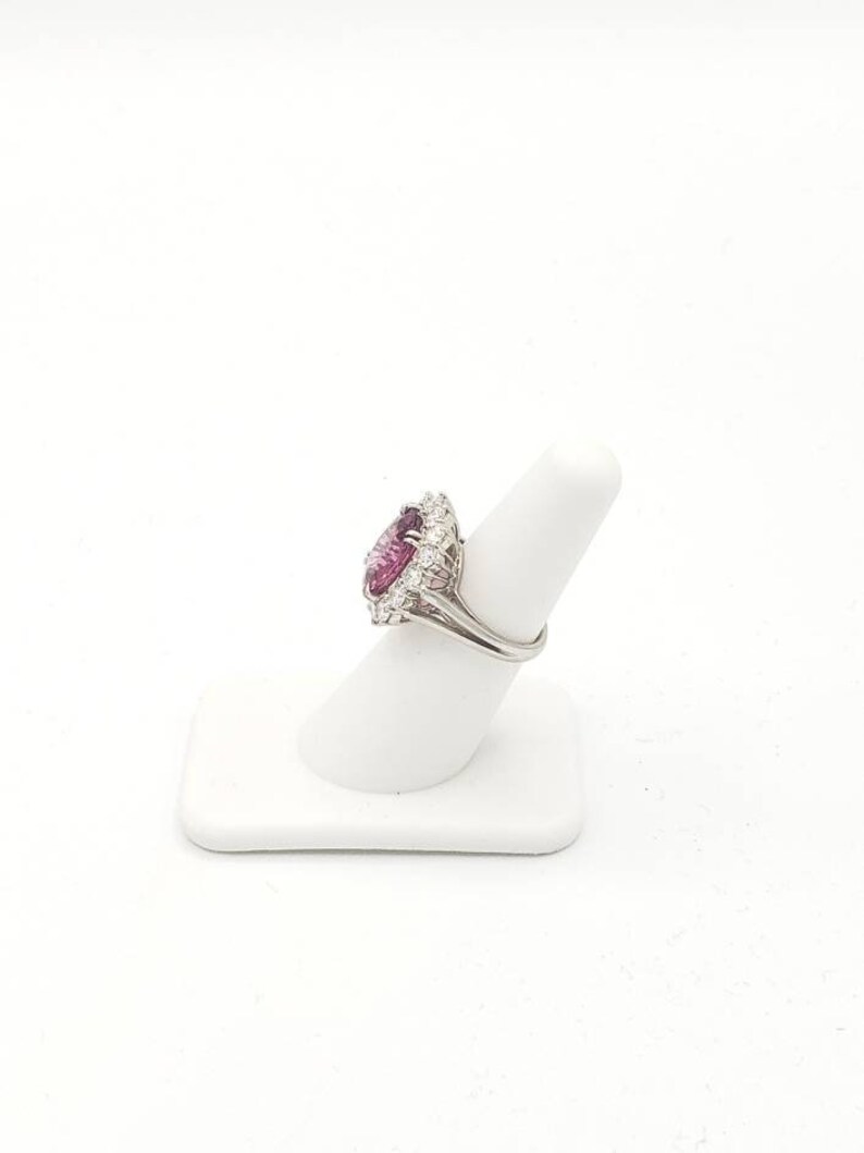 May include: A silver ring with a large, heart-shaped pink gemstone surrounded by smaller, clear gemstones.