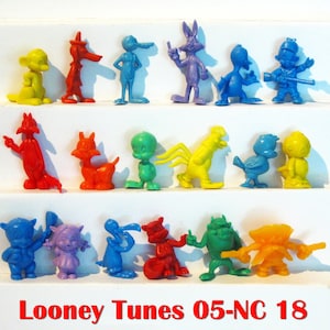 May include: A collection of colorful Looney Tunes figurines, including Bugs Bunny, Daffy Duck, and others. The figurines are in various poses and colors, such as yellow, red, blue, and green. The text "Looney Tunes 05-NC 18" is displayed at the bottom.