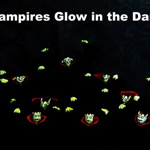 May include: A group of green glowing vampire figures with red capes against a black background. The text "Vampires Glow in the Dark" is at the top of the image.