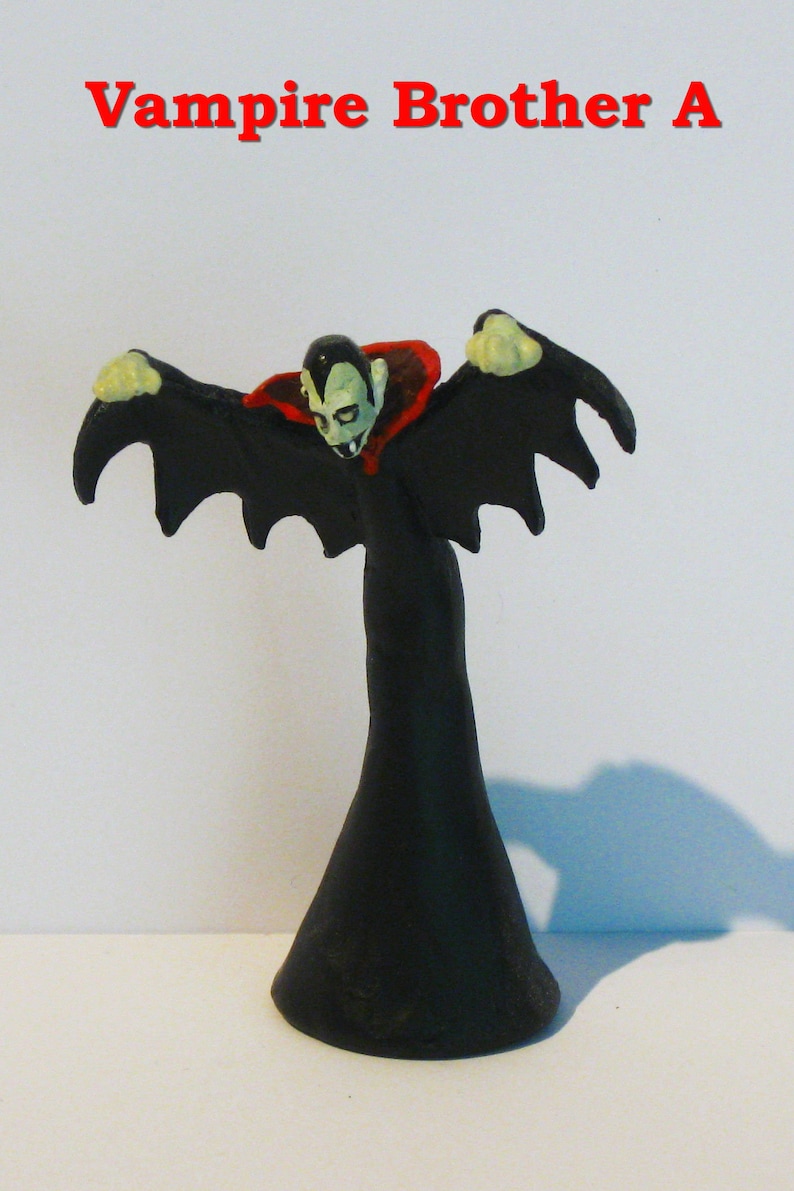 May include: A black plastic vampire figurine with red and white accents. The vampire has a cape and wings and is in a flying pose.