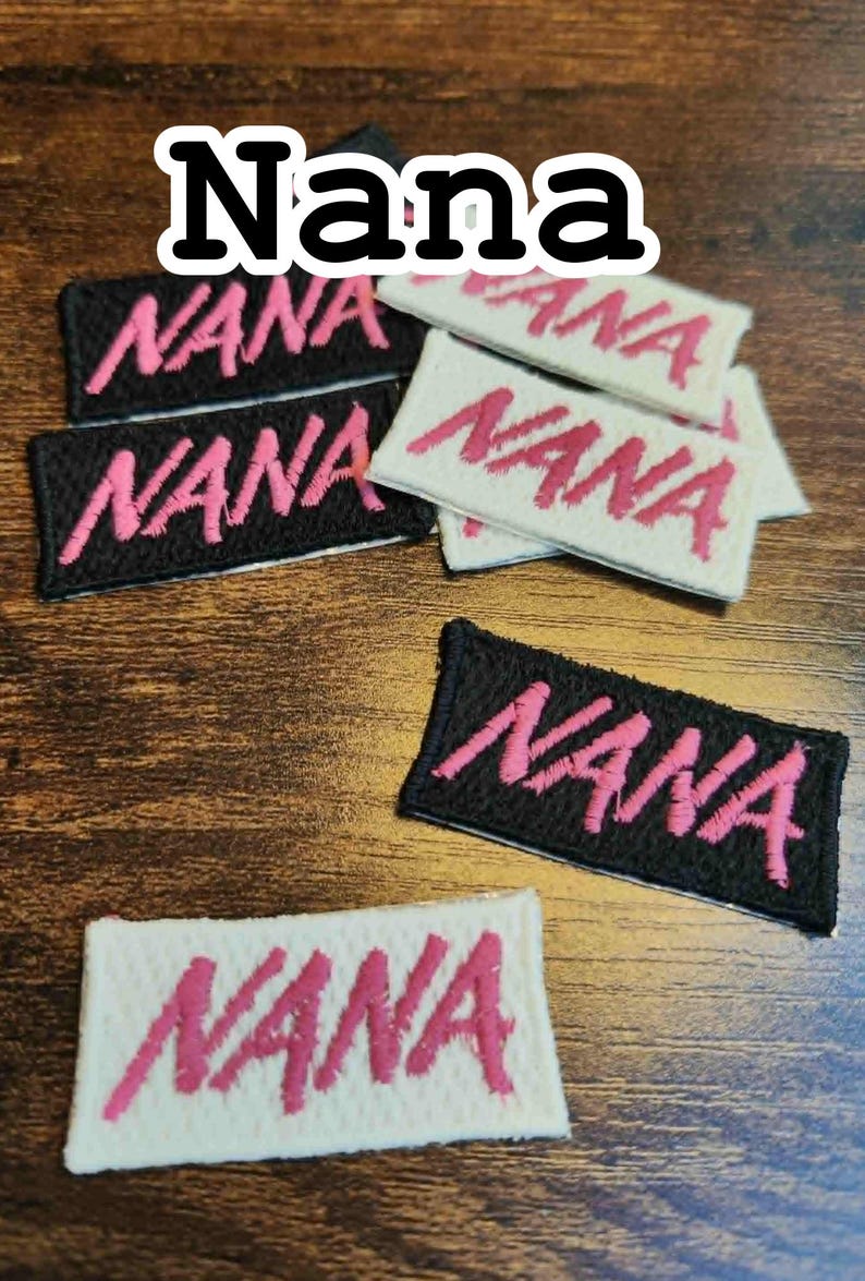 Może przedstawiać: Haftowane naszywki z napisem "Nana" w r&oacute;żowym skrypcie. Niekt&oacute;re naszywki są na czarnym materiale, inne na białym. Naszywki są prostokątne i mają obszyte obramowanie. Słowo "Nana" jest r&oacute;wnież wyświetlane powyżej.
