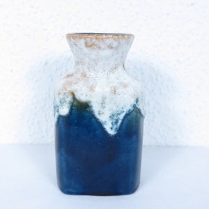 Pode incluir: Um vaso de cerâmica azul e branco com um esmalte texturizado. O vaso tem uma boca larga e uma base estreita.