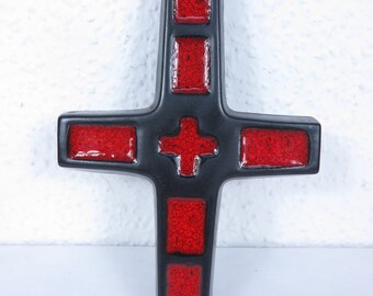 Könnte beinhalten: Ein schwarzes Kreuz mit roten, strukturierten Inlays. Das Kreuz hat eine glänzende Oberfläche und ein kleineres rotes Kreuz in der Mitte. Das Design ist symmetrisch vor einem strukturierten weißen Hintergrund.