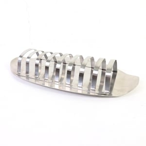 Puede incluir: Un tostador de acero inoxidable con una base curva y múltiples ranuras arqueadas para sostener rebanadas de pan. El soporte tiene una superficie pulida y reflectante y está diseñado para mantener la tostada en posición vertical.