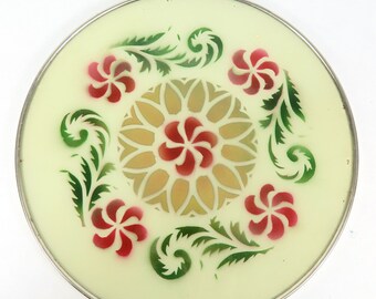 Op de afbeelding: Een ronde serveerschaal met een zilveren rand en een lichtgroene achtergrond. De schaal heeft een bloemmotief met rode en groene bloemen en bladeren.