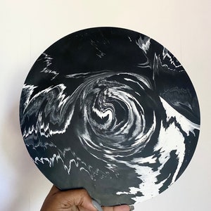 Pu&ograve; includere: Un vassoio circolare nero e bianco con un motivo a spirale di marmo. Il vassoio &egrave; realizzato in resina e ha una finitura liscia e lucida.