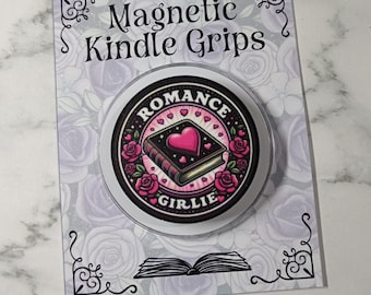 Puede incluir: Un agarre magnético circular para Kindle con una ilustración de un libro negro con un corazón rosa, rodeado de rosas rosas y el texto 'ROMANCE GIRLIE'. El agarre está montado en una tarjeta de presentación rectangular con un patrón floral y el texto 'Magnetic Kindle Grips'.