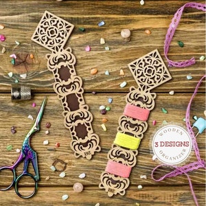 May include: Two wooden thread organizers with intricate laser cut designs. Each organizer has three slots for holding thread spools. The organizers are on a wooden surface with colorful confetti scattered around them. The text "WOODEN 3 DESIGNS ORGANIZER" is visible in the image.