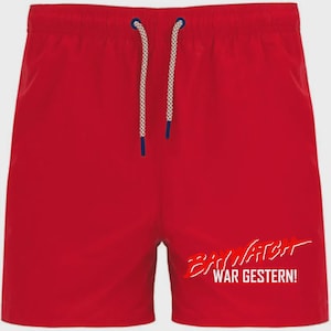 Könnte beinhalten: Leuchtend rote Badeshorts mit weißem Kordelzug und dem Text "BAYWATCH WAR GESTERN!" in Weiß und Rot. Die Shorts eignen sich zum Schwimmen oder für Freizeitaktivitäten.